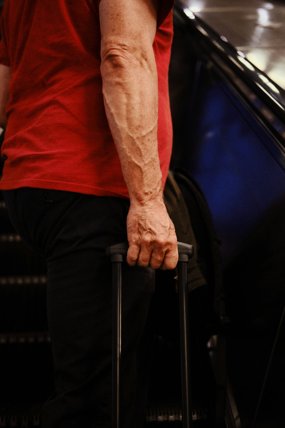 A man with a red shirt and black pants holding a suitcase