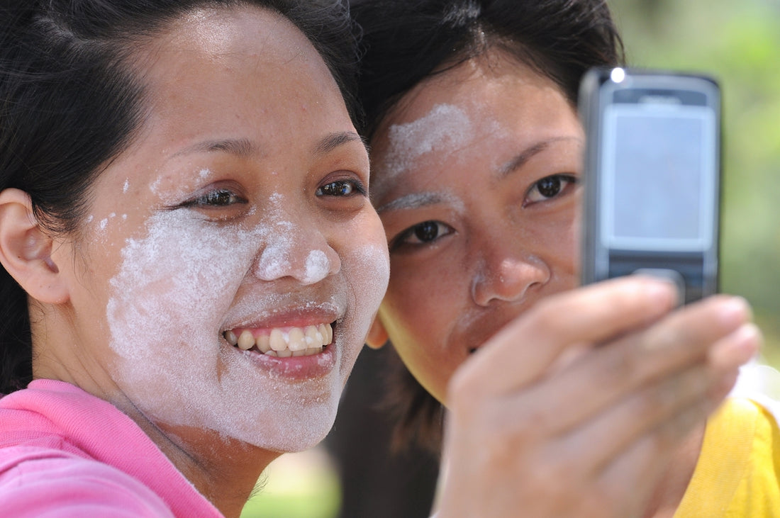 Two women take a selfie, faces with white substance.