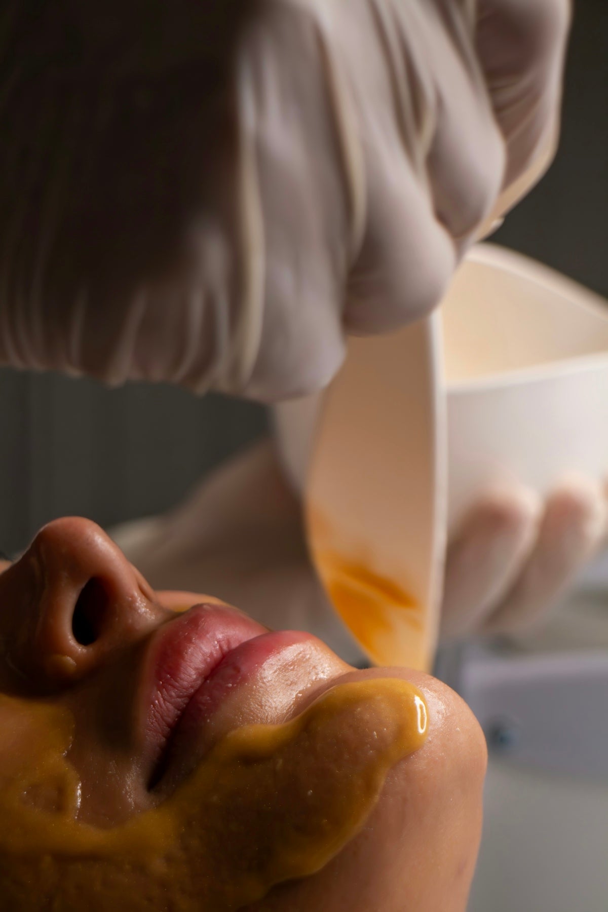 Beautician applying facial mask to woman's face