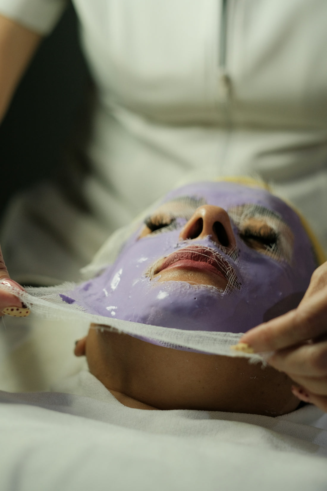 Purple facial mask being removed from a woman's face.