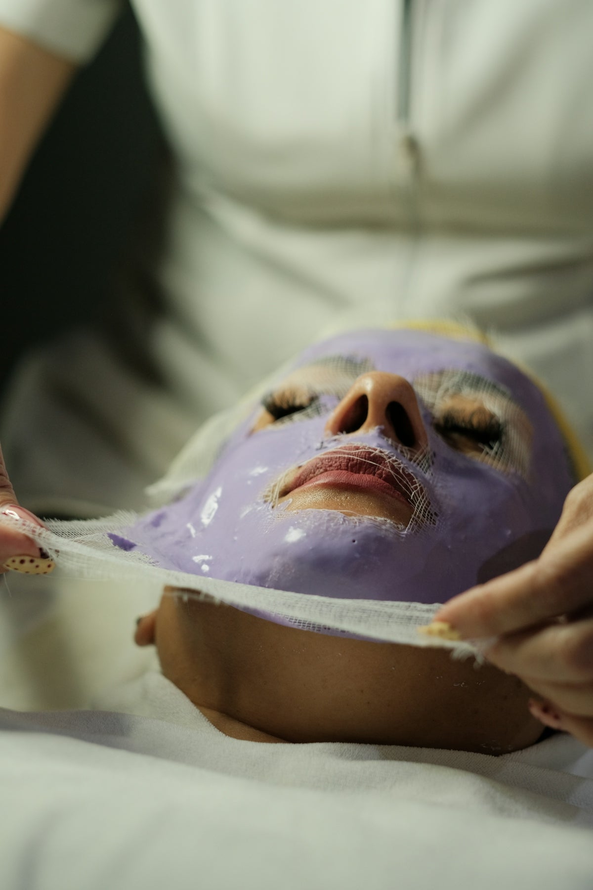 Purple facial mask being removed from a woman's face.