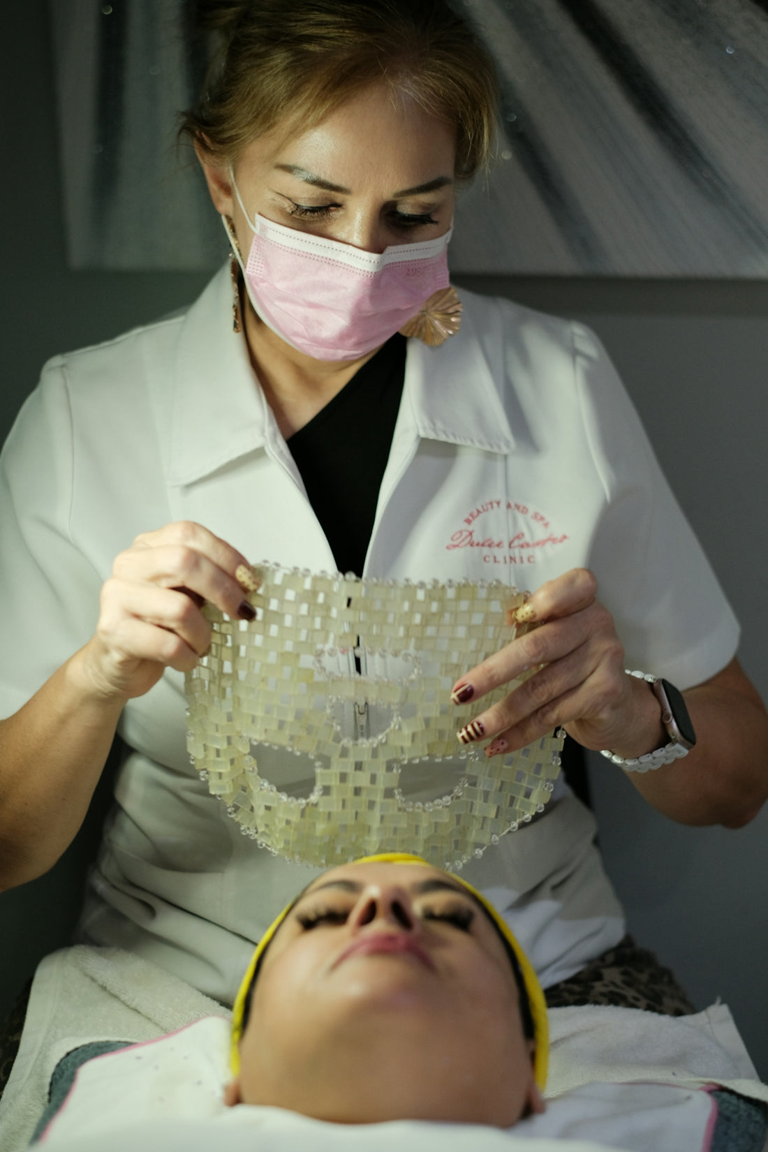 Woman applies a clear textured mask to another woman's face.