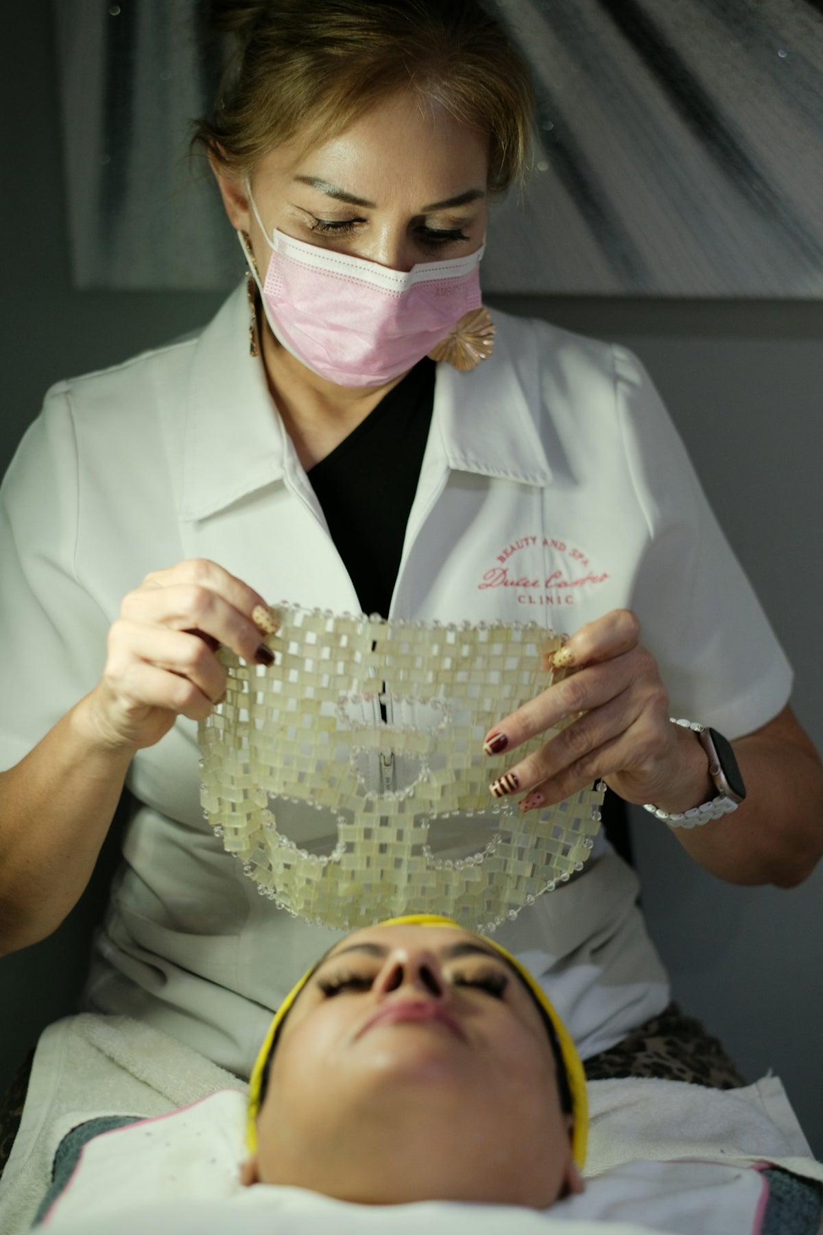 Woman applies a clear textured mask to another woman's face.